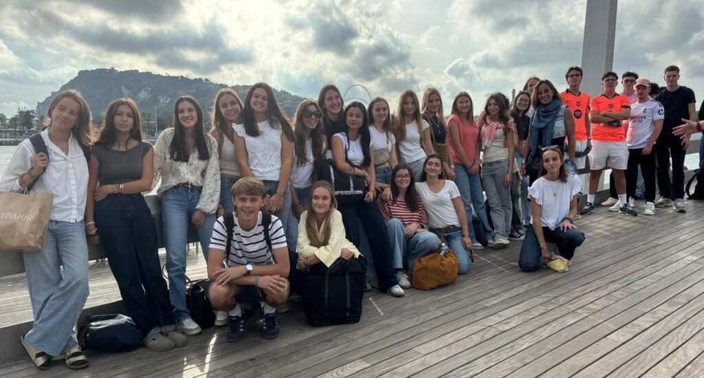 Un groupe d'élèves français en voyage scolaire posant avec enthousiasme à Barcelone, Espagne.